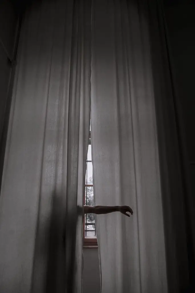 person standing beside the curtain and rising their arms
