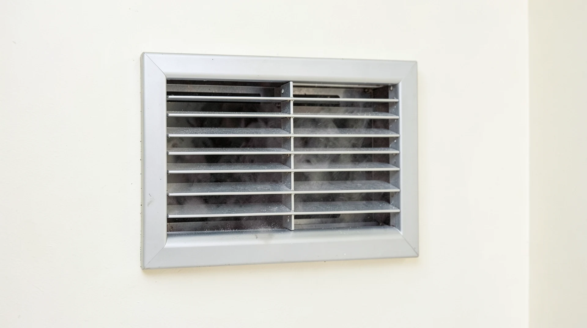 Wall-mounted exhaust vent drawing damp air out of a room to lower humidity